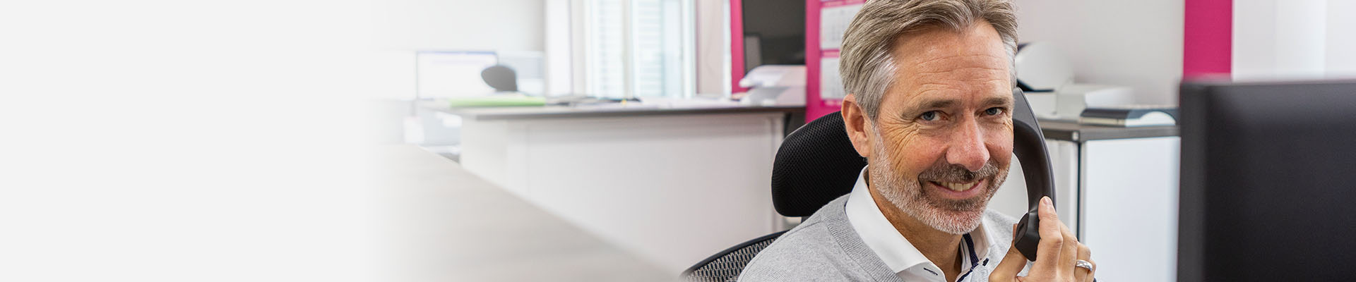 Lächelnder Ansprechpartner telefoniert am Schreibtisch im Büro.